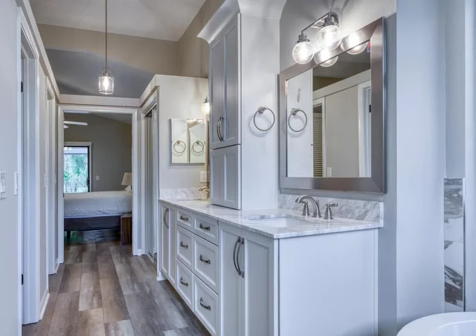 Master bathroom with white cabinetry, marble countertop, framed mirrors, and painted walls in neutral tones