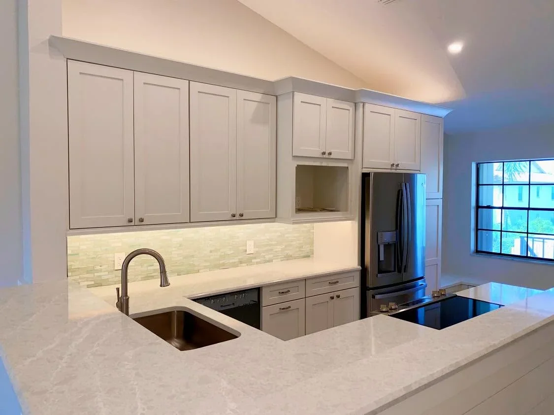 White cabinetry, green tile backsplash, quartz counters, black stainless appliances in modern kitchen
