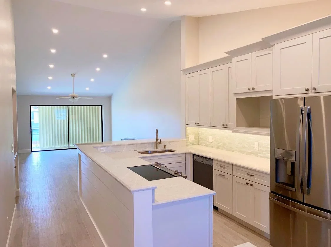 White kitchen cabinets, marble countertops, stainless steel appliances, island with cooktop and sink