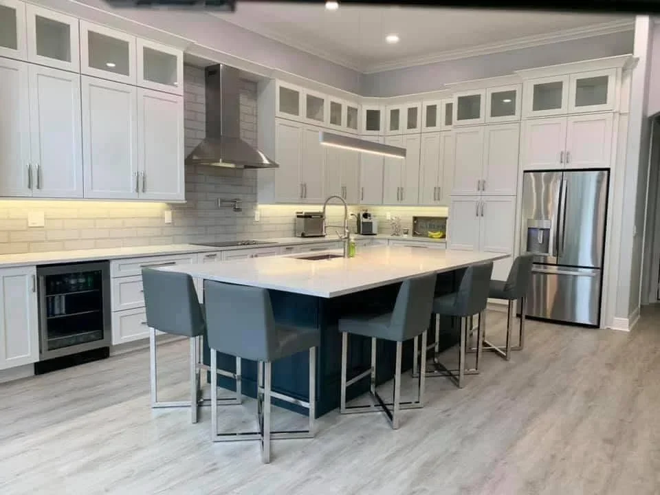 White kitchen cabinets with dark blue island, quartz countertop, subway tile backsplash, stainless steel appliances