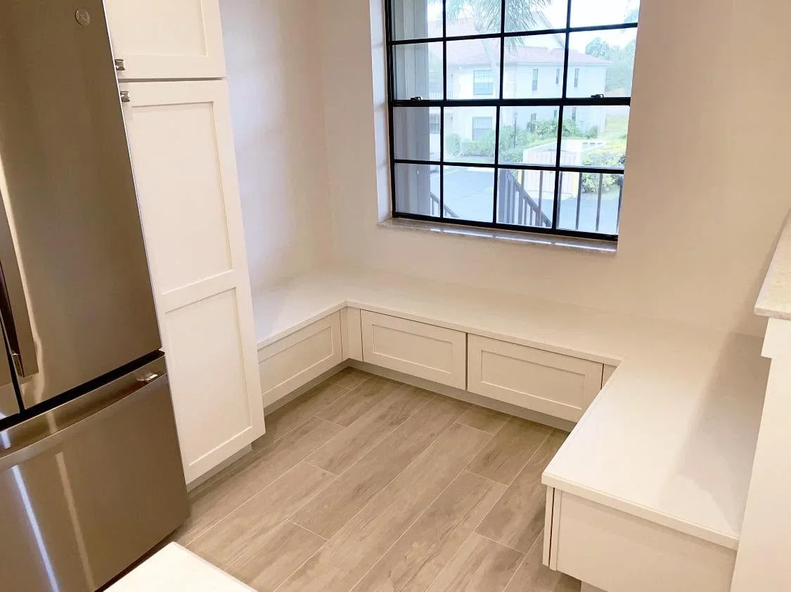 Kitchen nook with cream cabinetry, wood flooring, and black-framed window