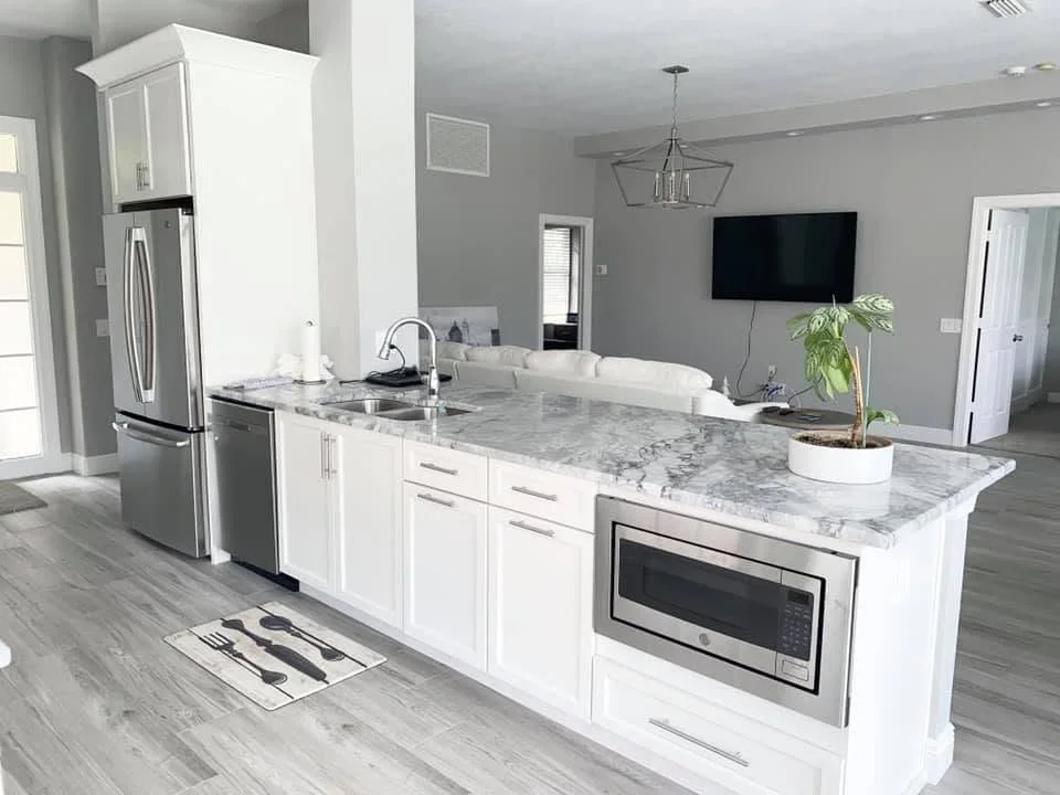 Gray painted walls with white kitchen cabinets, marble countertop island, and stainless steel appliances